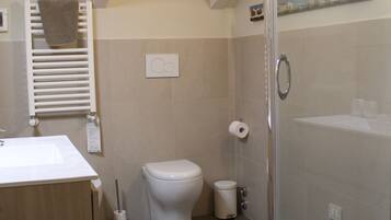 Ein modernes Badezimmer mit Glasdusche, Toilette und Waschbecken mit Handtuchhalter.