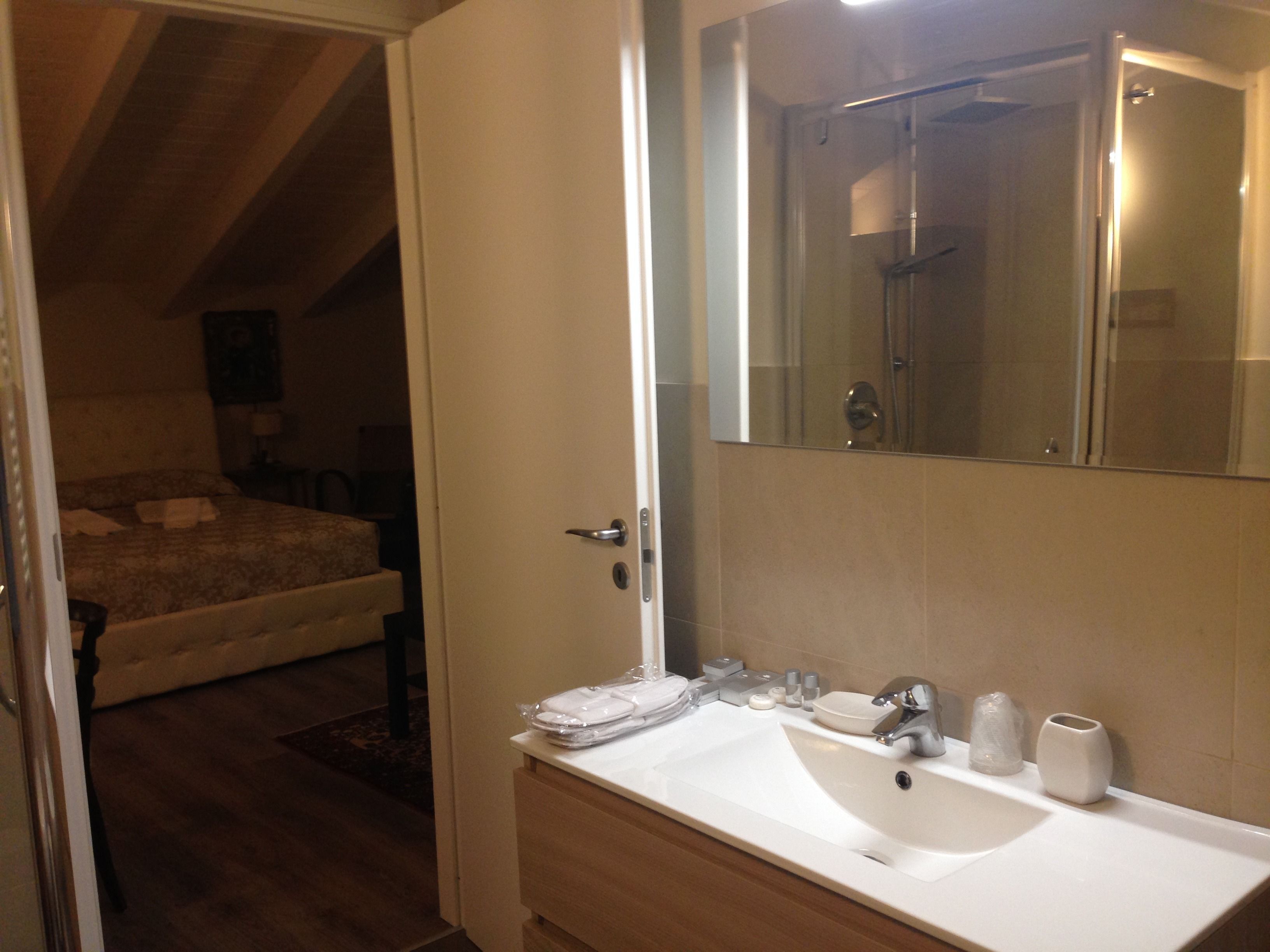 A hotel bathroom with a sink, mirror, and toiletries.