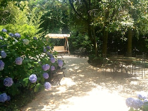 Um jardim com pérgola, área de estar e um caminho pavimentado.