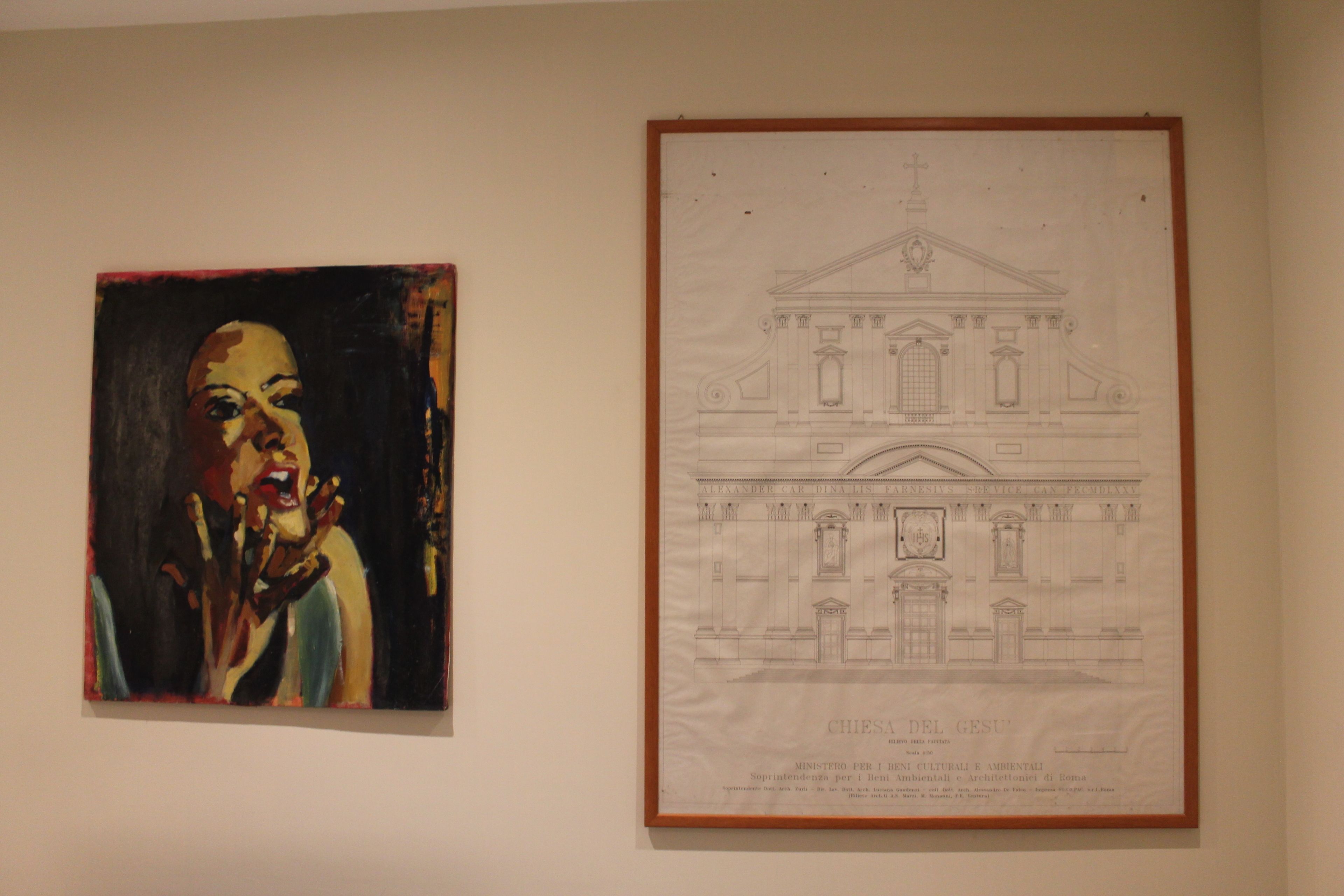 A framed architectural drawing of a building with columns and a pediment, and a colorful painting of a person.