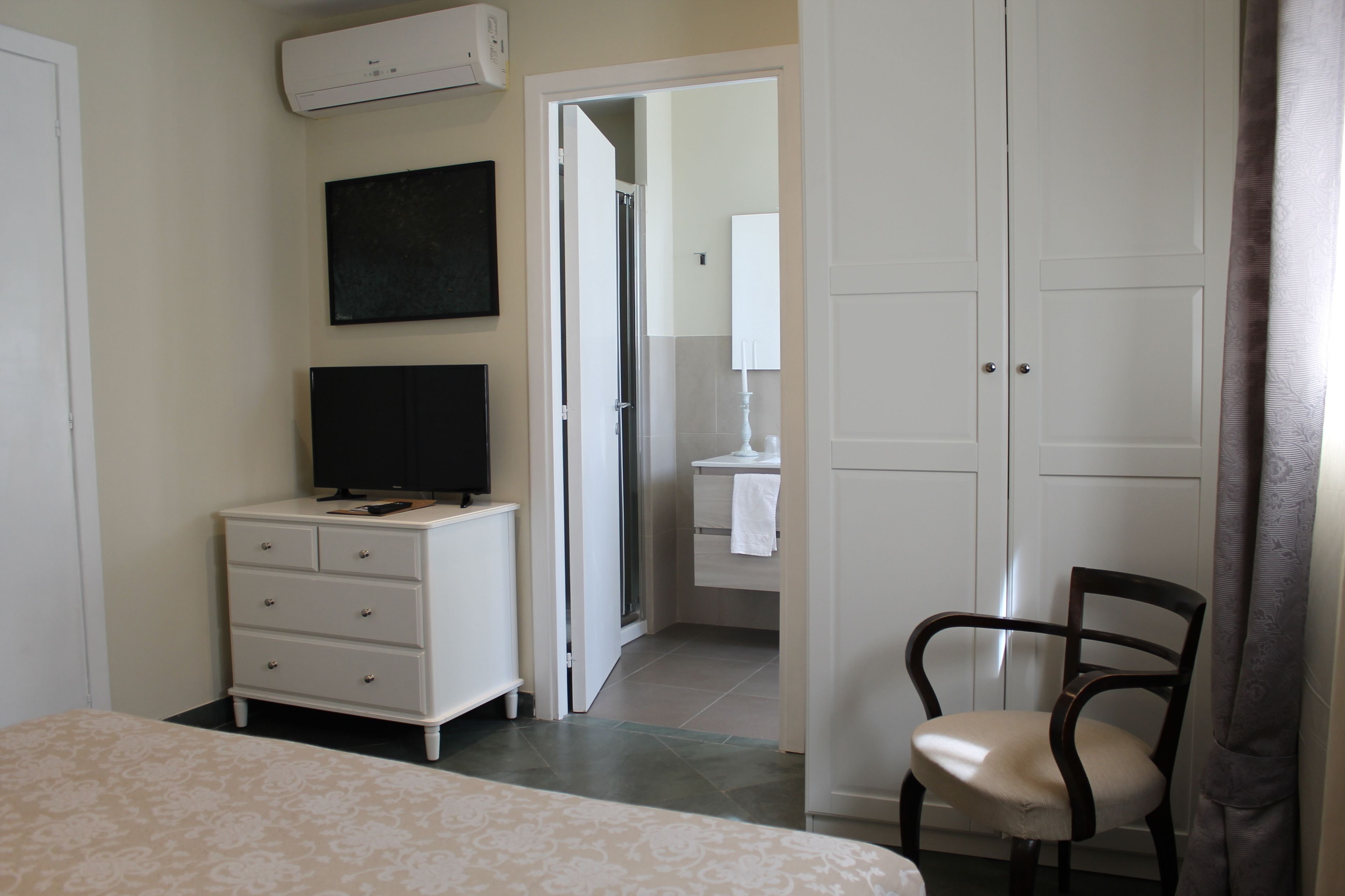 Un dormitorio con cama, cómoda, televisor y una silla.