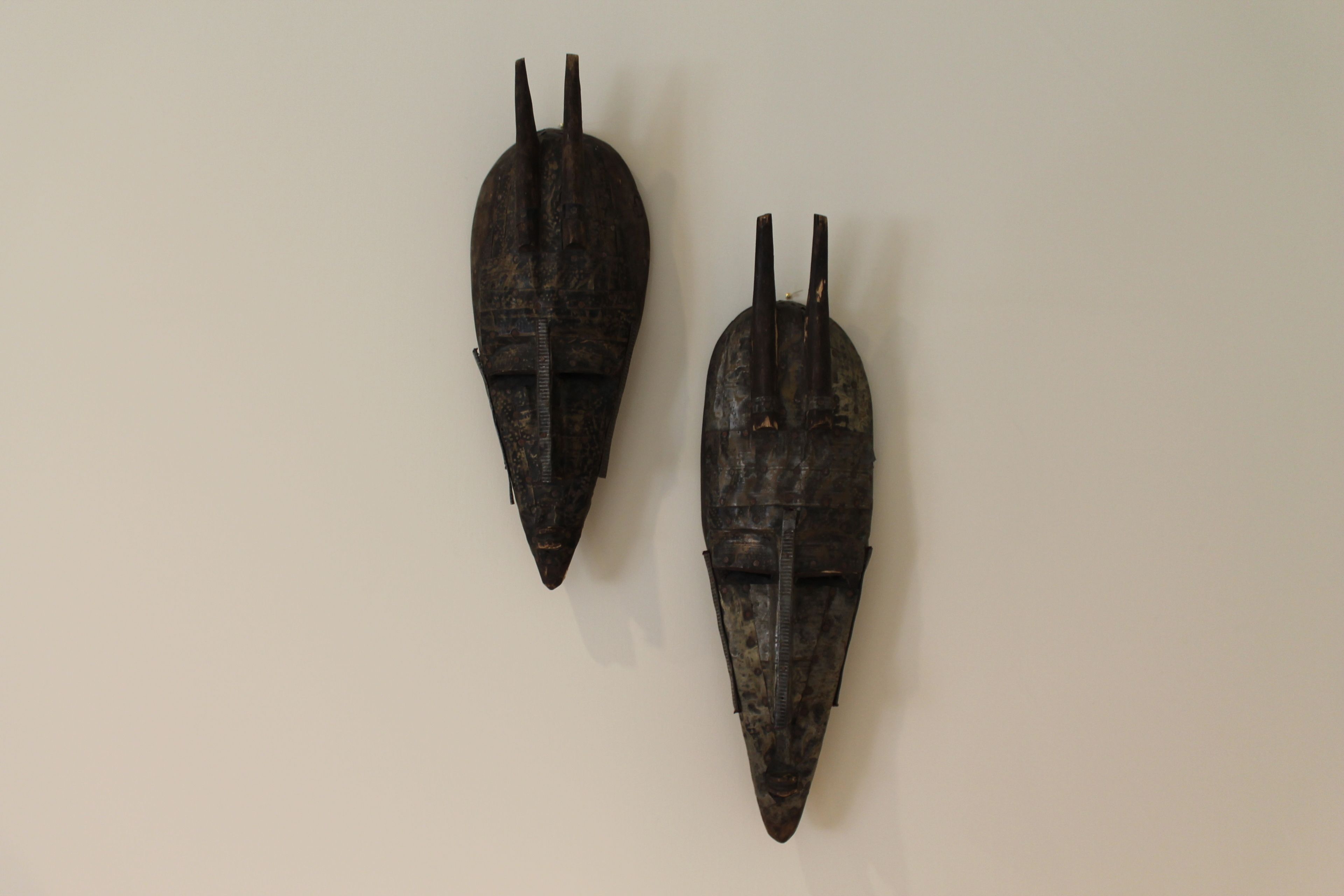 Deux sculptures en bois fixées sur un mur sobre.