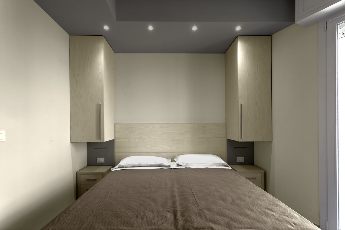 Quarto com cama, duas mesas de cabeceira e armários embutidos.