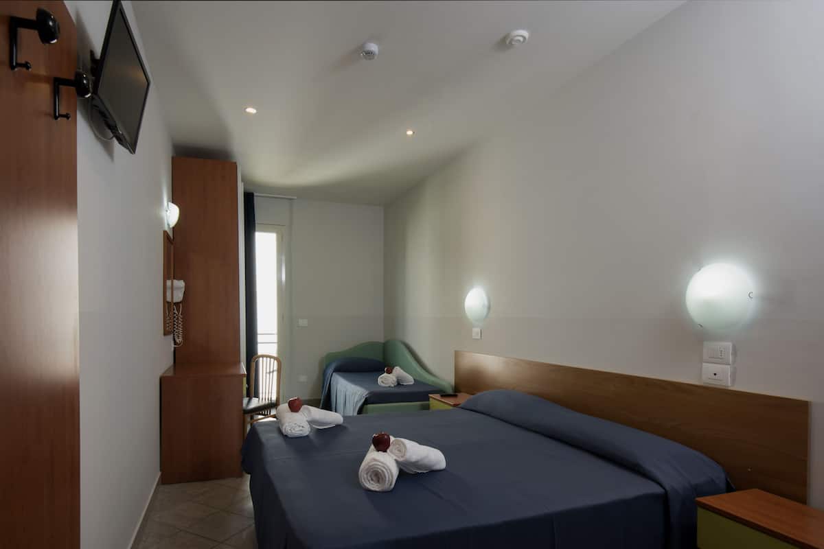 Quarto de hotel com duas camas, uma televisão e um espelho.