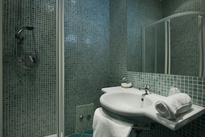 A bathroom with a glass shower enclosure, a white sink, and a mirror. - Hotel Scarlet (Rimini)
