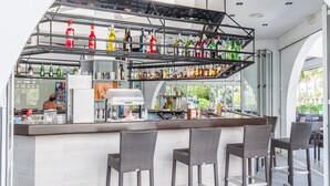 Un'area bar con diverse bottiglie di liquore, una macchina da caffè e sgabelli da bar.