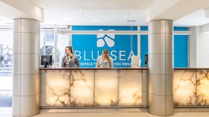 Una reception hotel con un cartello blu che recita "BLUESEA HOTELS YOU SMILE".
