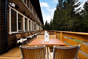 A wooden deck with a table and chairs, overlooking a forested area. - Eko sport hotel Björnson (Demanovska Dolina)