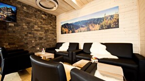 A cozy room with a stone wall, a large window with a mountain view, and a television on the left. - Eko sport hotel Björnson (Demanovska Dolina)