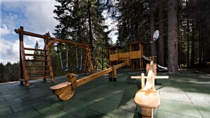 A playground with a seesaw, a swing set, and a basketball hoop. - Eko sport hotel Björnson (Demanovska Dolina)