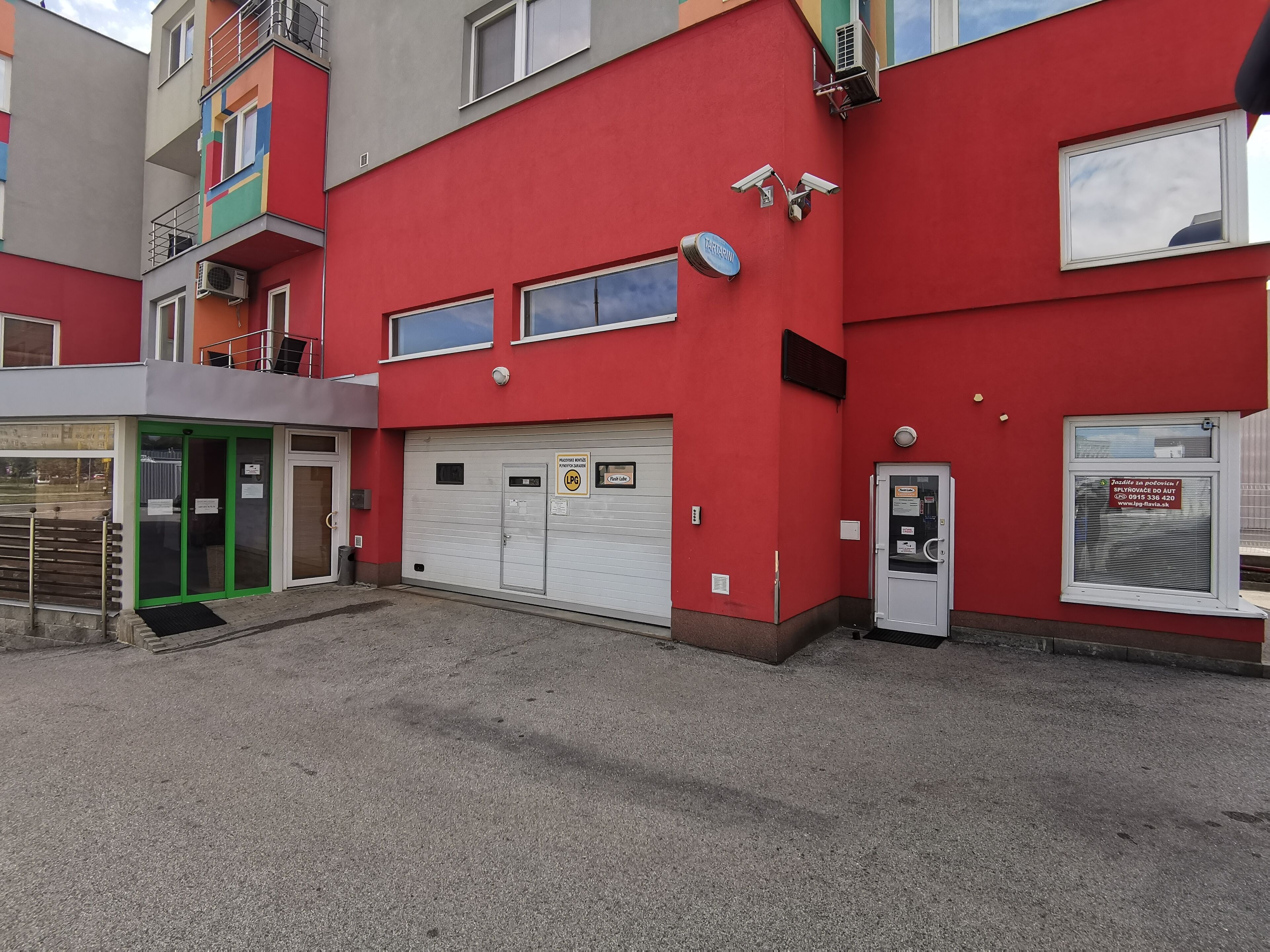 A red building with a garage door, security cameras, and a sign indicating a garage space.
