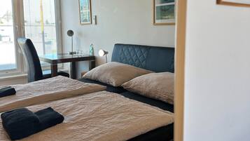 Habitación de hotel con dos camas, un escritorio y una silla. Se observa un equipo de aire acondicionado en la pared.