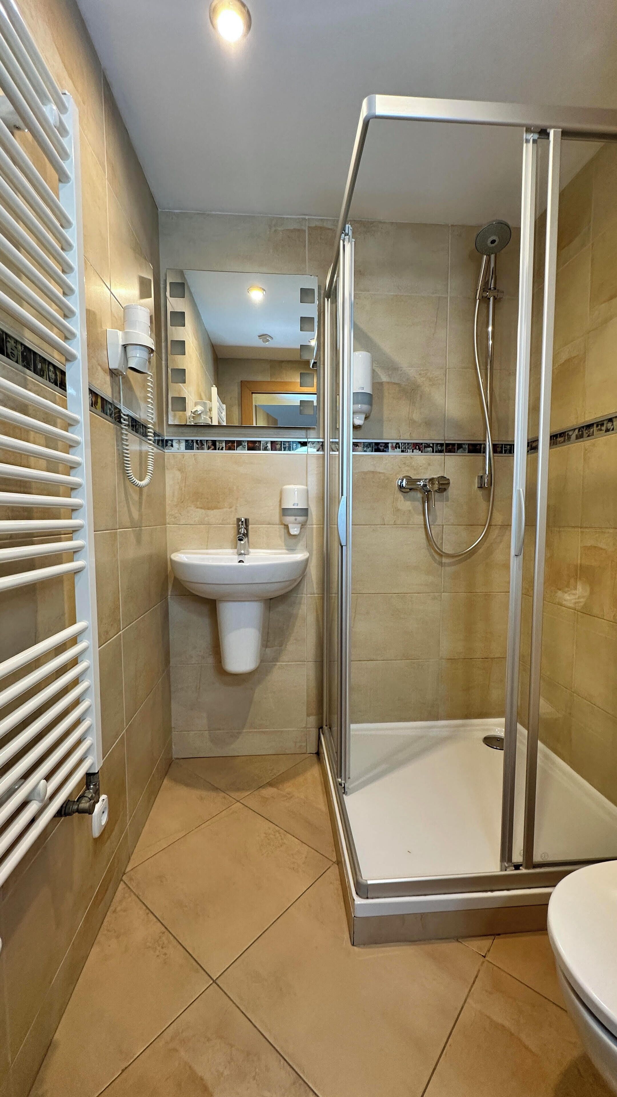 Un baño moderno con ducha envuelta en vidrio, un lavamanos y un perchero para toallas.
