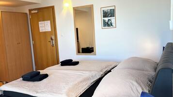 A neatly made bed with a blue headboard, a bedside table with a lamp, and a wooden door with a sign.