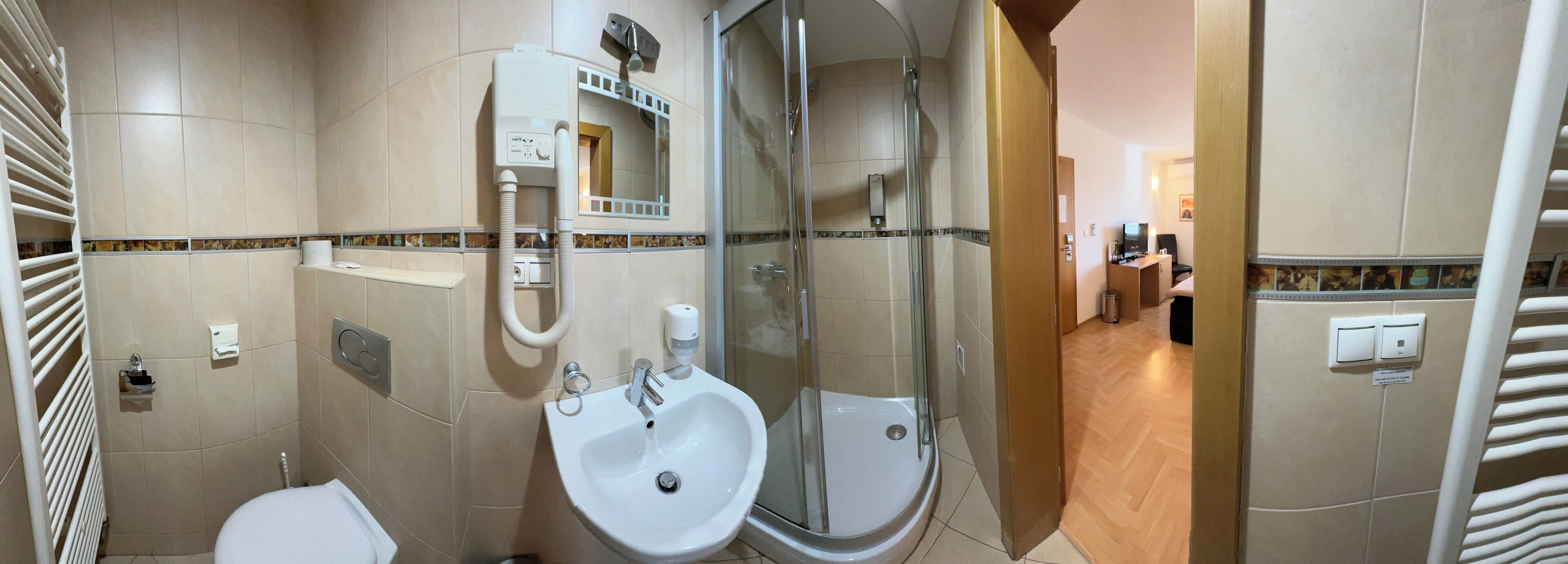 Un baño moderno con inodoro, dos lavamanos, ducha envuelta en vidrio y un perchero para toallas.