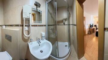 A modern bathroom with a toilet, two sinks, a glass-enclosed shower, and a towel rack.
