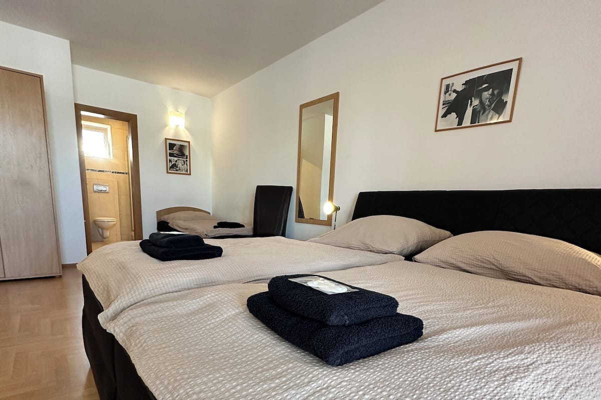 A hotel room with a large bed, a bedside table, a mirror, and a picture on the wall.