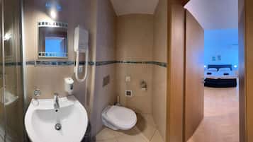A modern bathroom with a glass-enclosed shower, a white sink, and a toilet.