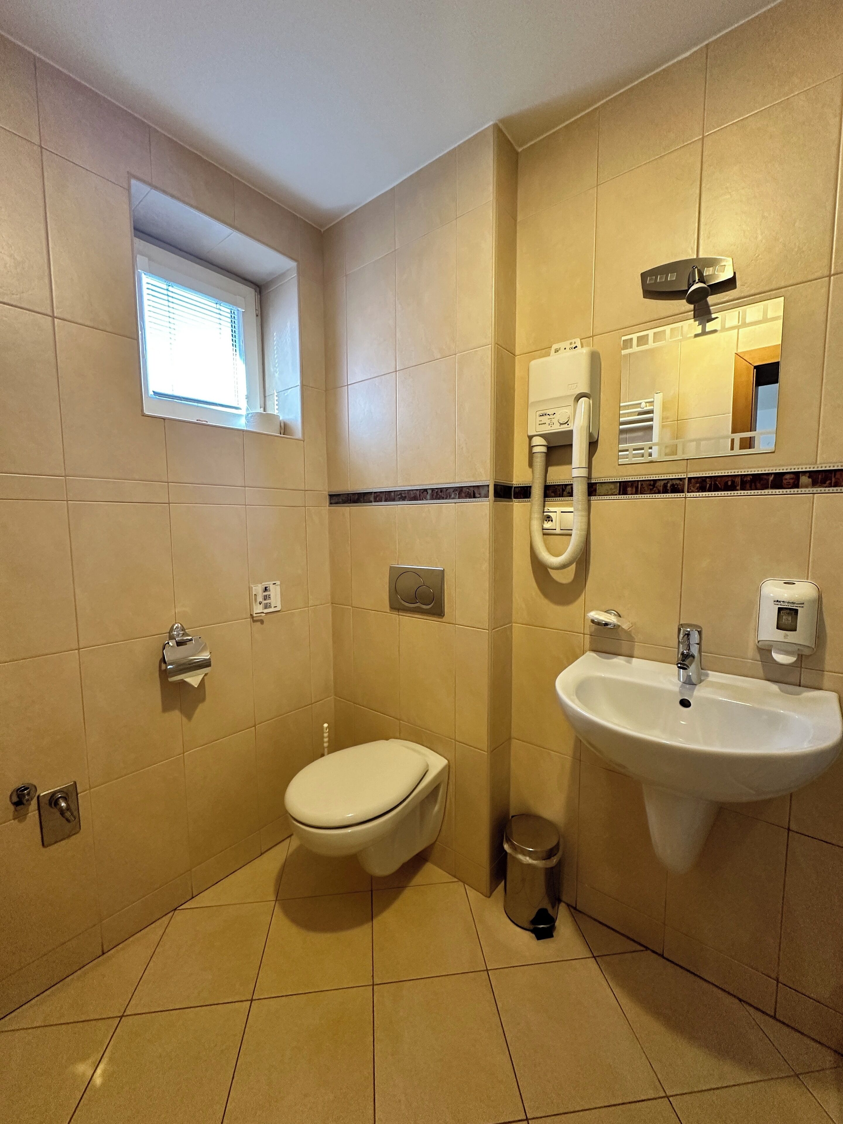 A bathroom with a toilet, sink, and window.