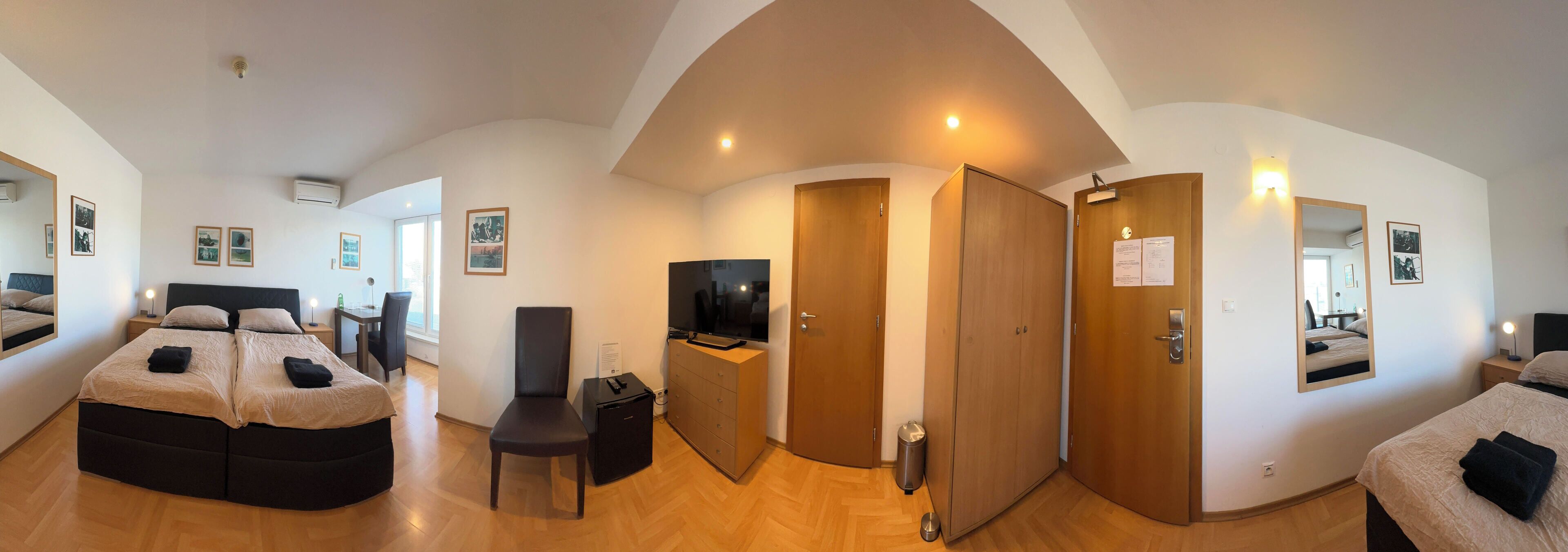 Amplia habitación de hotel con una cama grande, un escritorio, una silla, un armario y una televisión.
