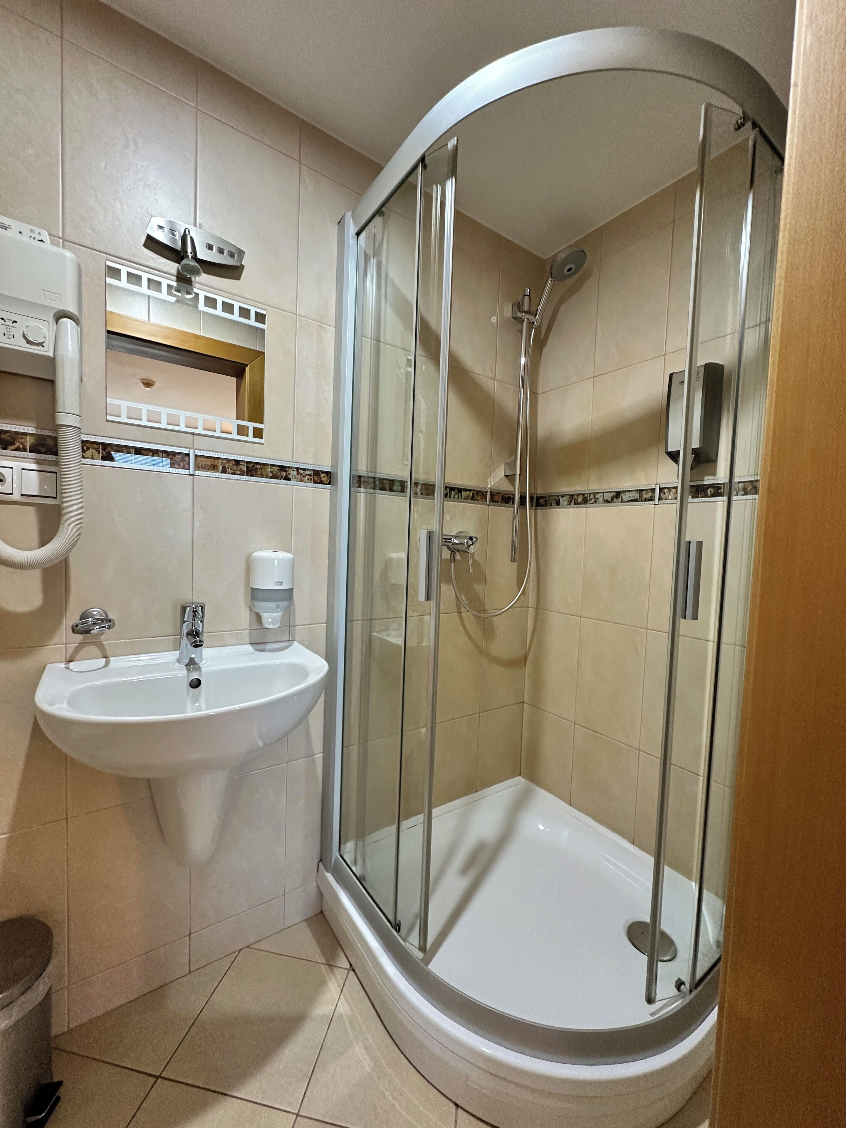 A bathroom with a glass-enclosed shower, a sink, and a mirror.