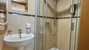 A bathroom with a glass-enclosed shower, a sink, and a mirror.
