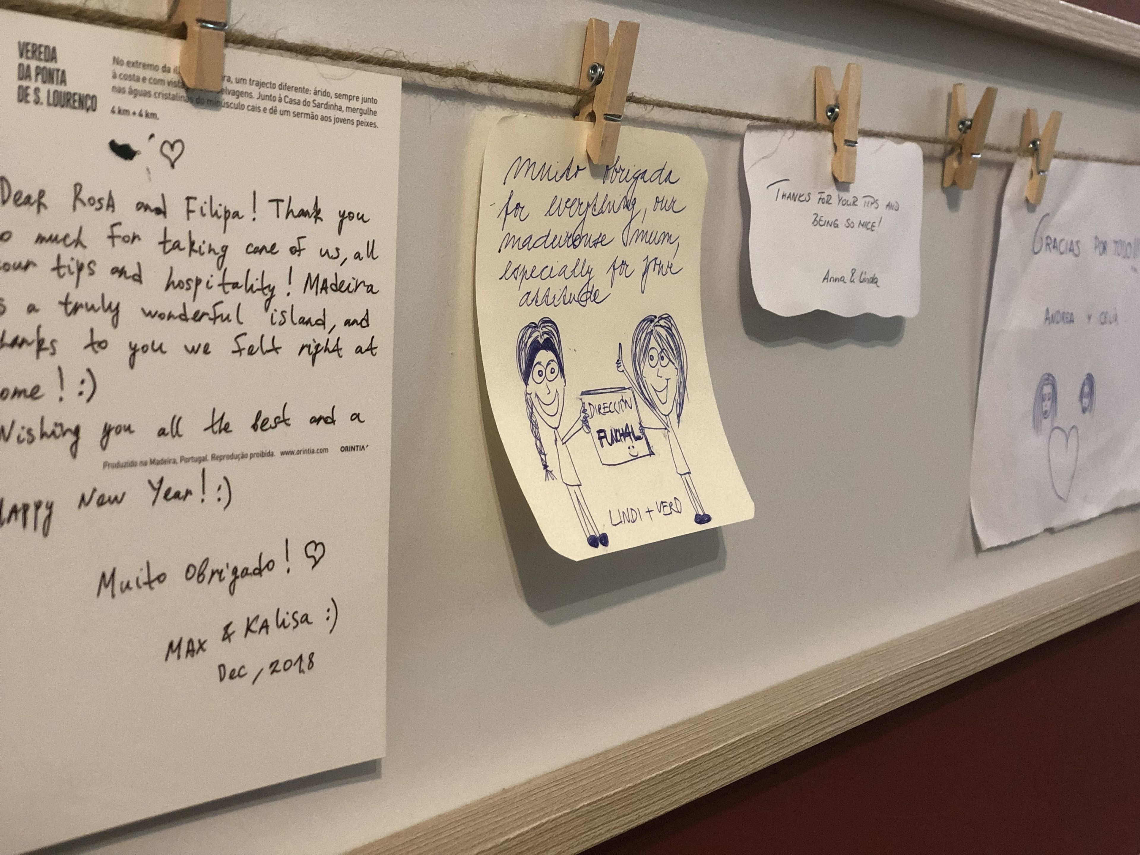 Un muro decorato con vari appunti e disegni, fissati con mollette da bucato.