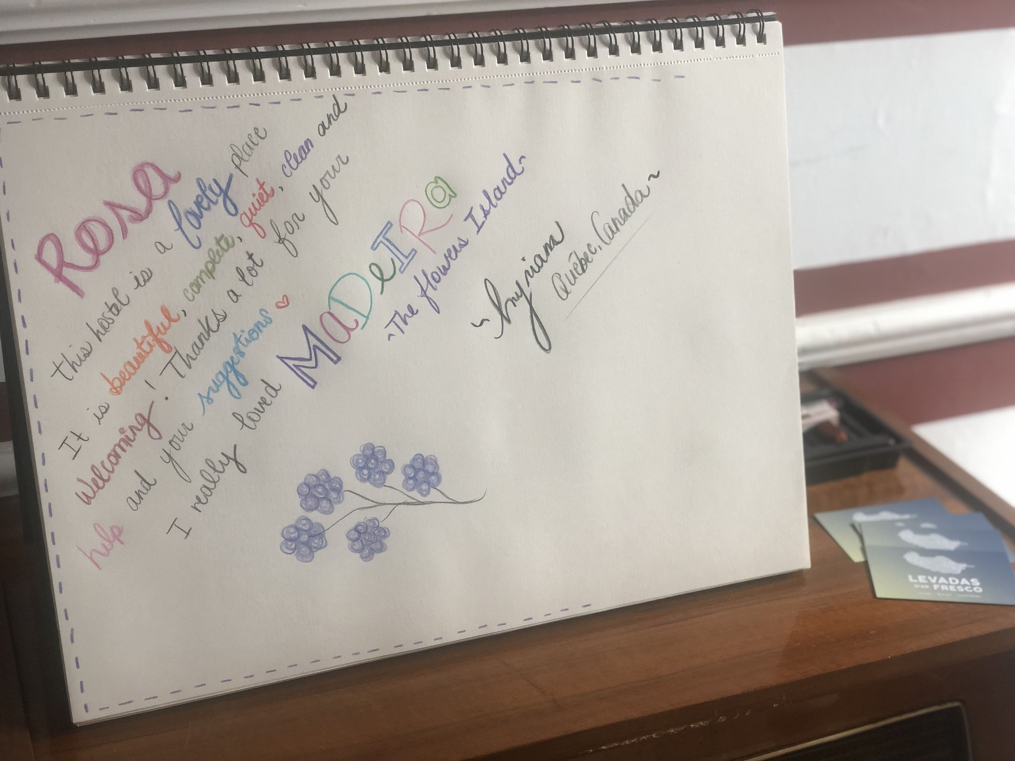 Een met de hand geschreven briefje in een notitieboekje met tekst en een bloemtekening.
