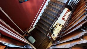 A wooden staircase with a checkered floor leading to a room with a desk and chair.