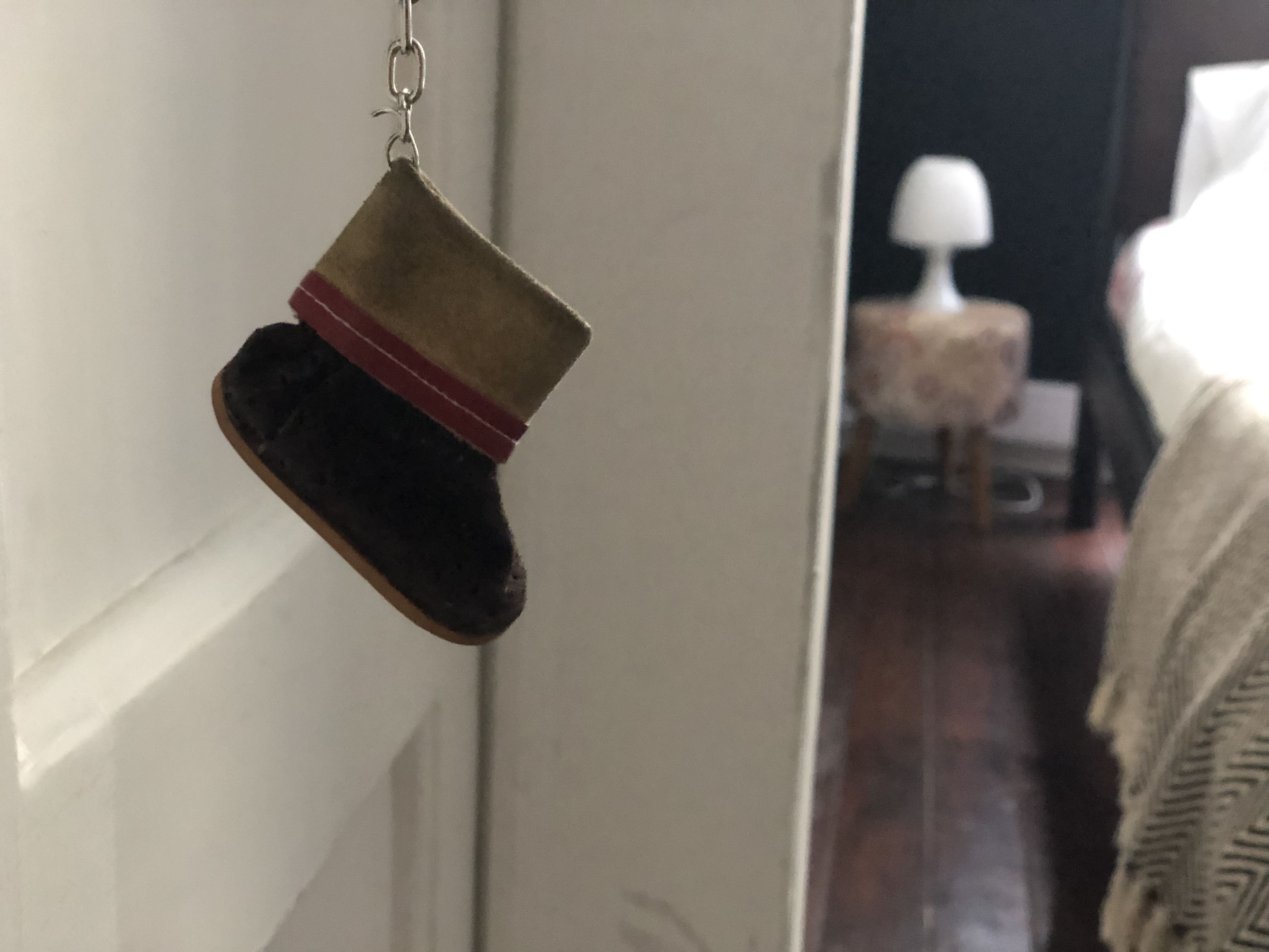 Un petit objet de couleur sombre, peut-être en cuir, suspendu à un mur blanc.