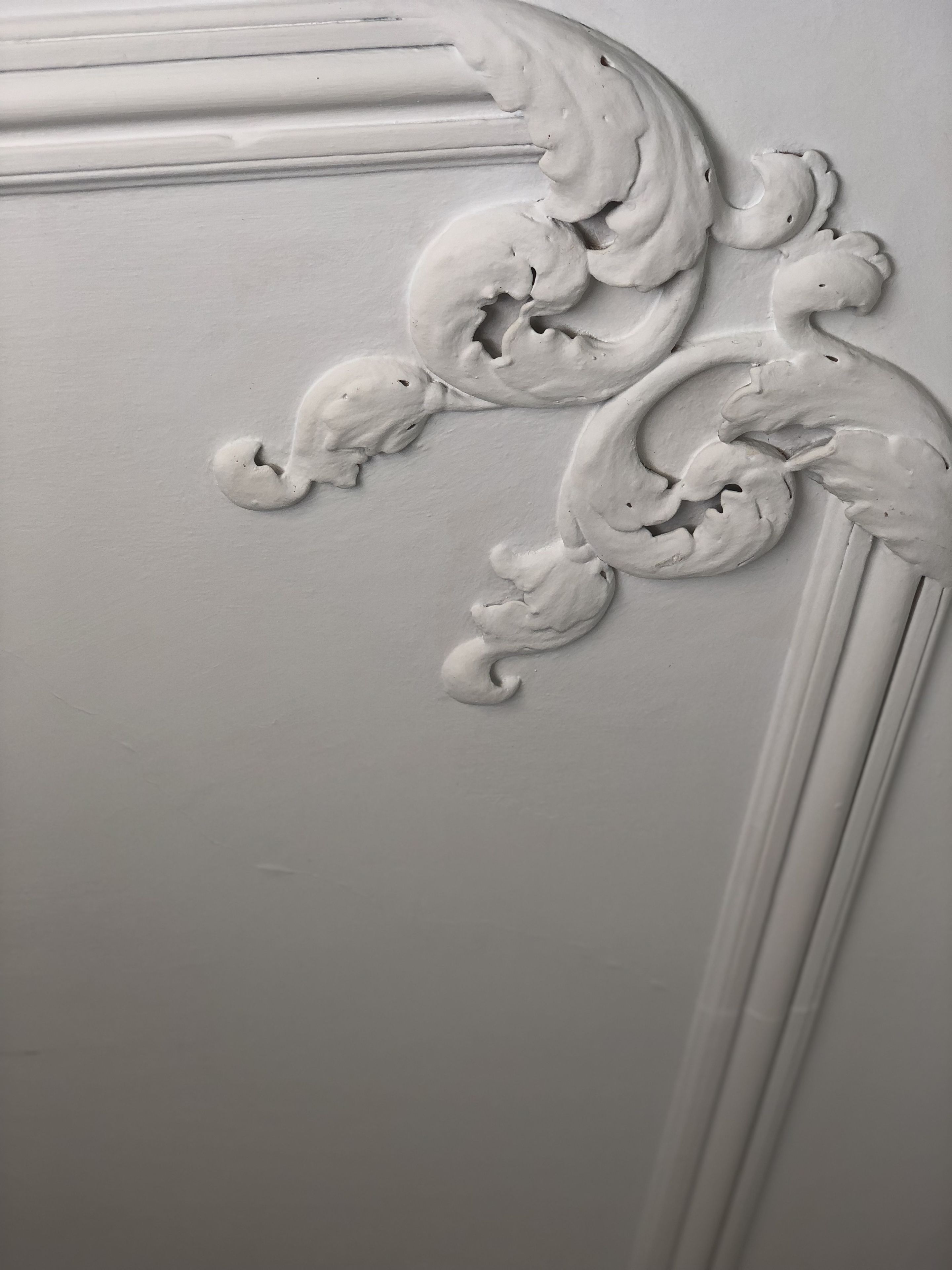 A close-up of a white decorative molding with intricate scrollwork.
