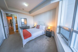 A bedroom with a bed, bedside tables, a mirror, and a window. - Lake View Luxury Condo by Elite Suites (Mississauga)