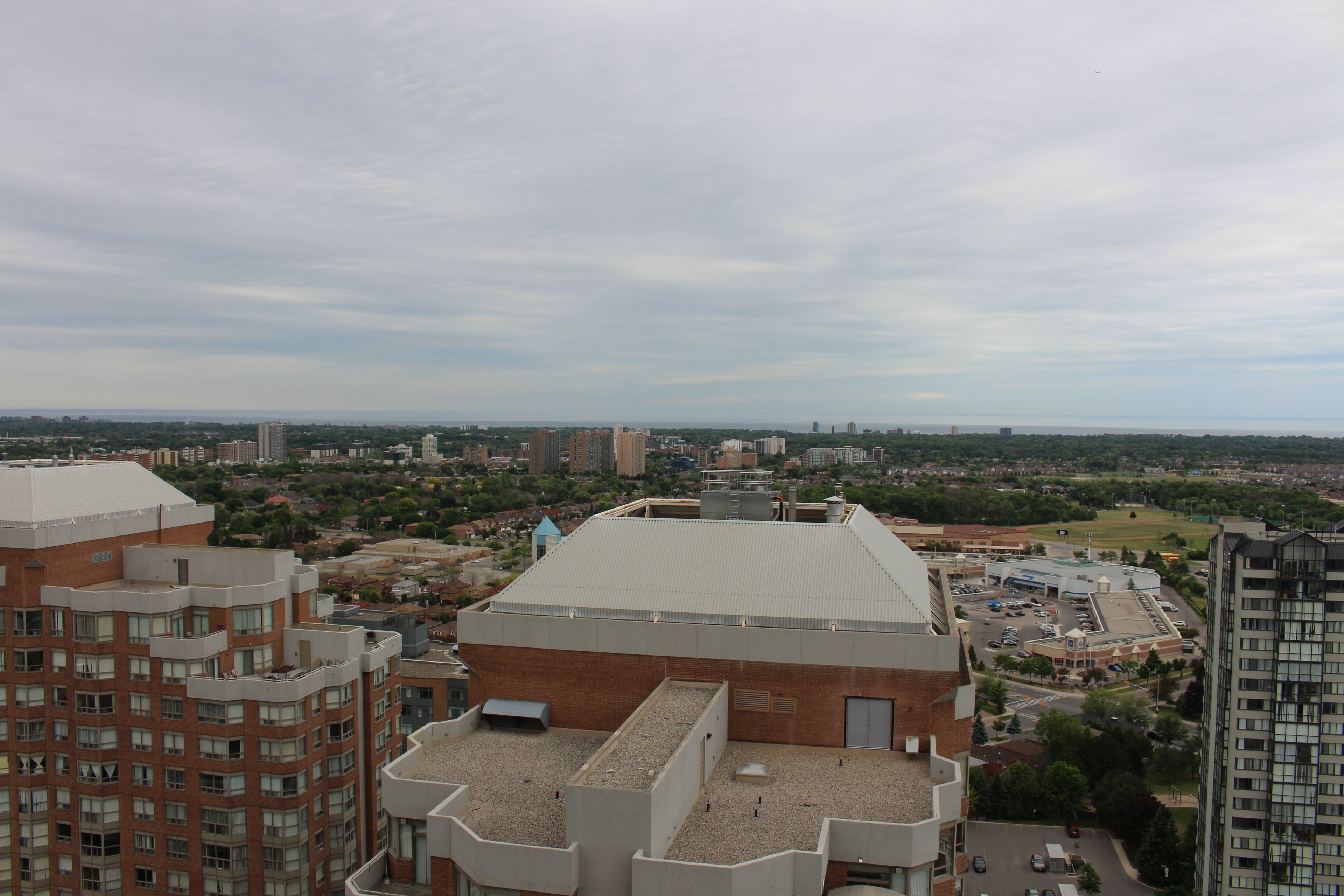 A high-rise building with multiple floors, a flat roof, and a view of a cityscape in the background.