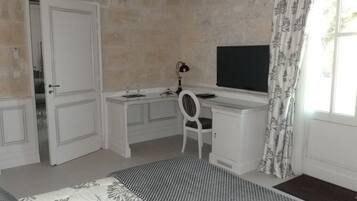 Une chambre à coucher comprenant un lit, un bureau, une chaise, un téléviseur et une armoire.