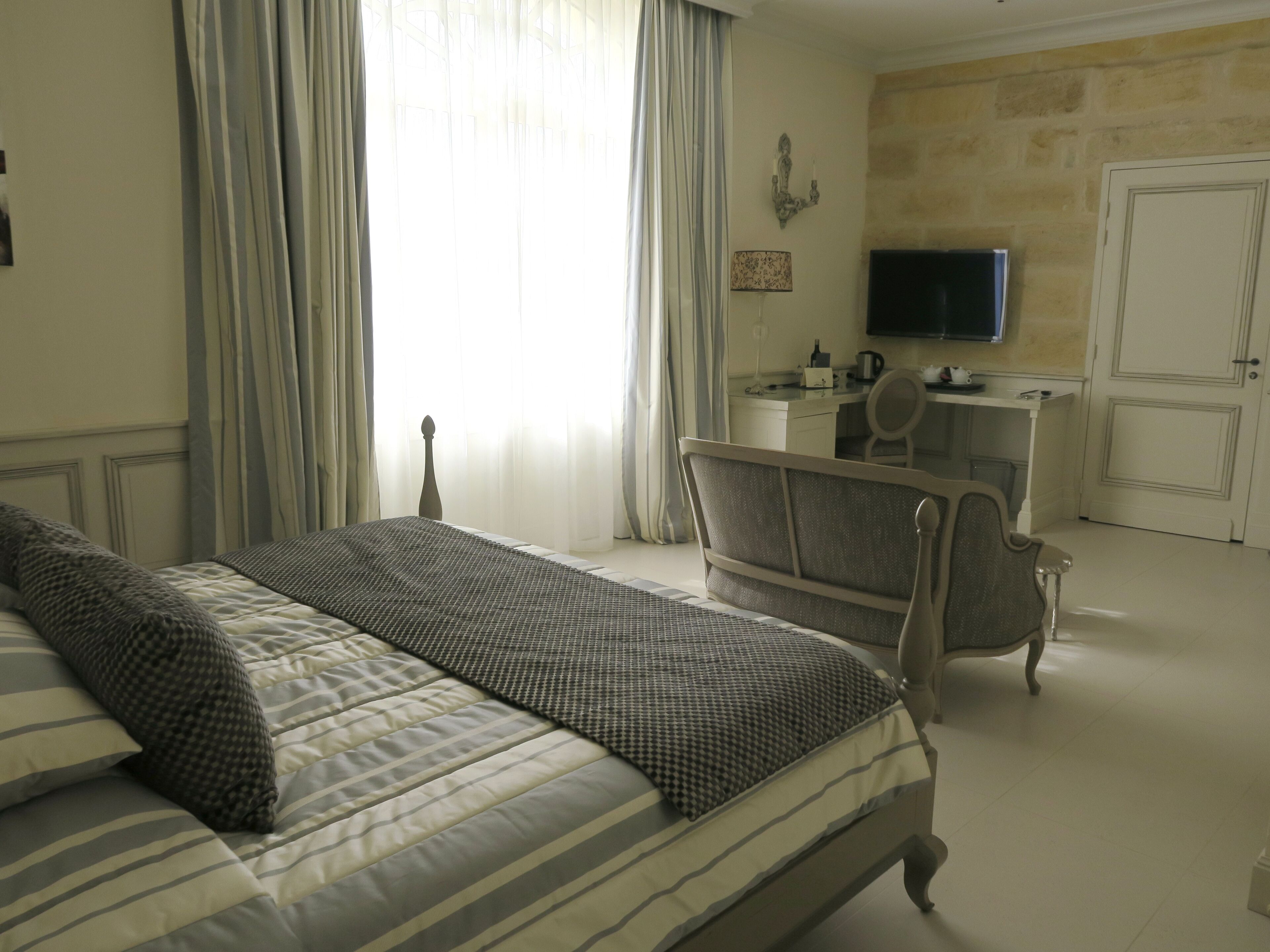 Une chambre d’hôtel avec un lit, un bureau, une chaise, une télévision et une porte.