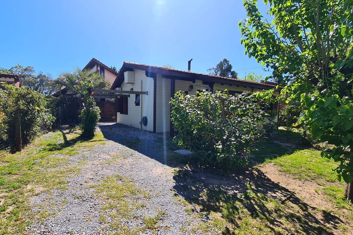 Una casa con camino de grava, rodeada de vegetación y un cielo despejado.