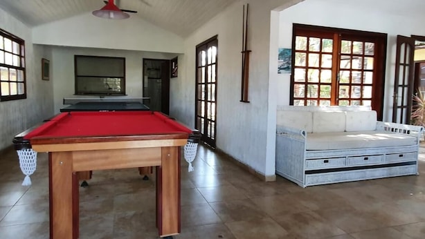 Una mesa de billar en una habitación con techos altos y ventanas amplias.