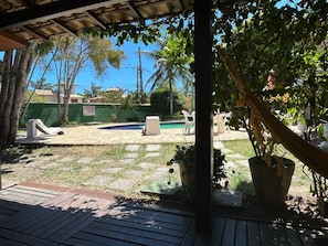 A covered outdoor area with a pool, lounge chairs, and potted plants.