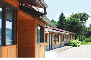 Une rangée de cabanes en bois dotées de grandes fenêtres et reliées par une passerelle couverte.