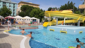 A swimming pool area with a water slide and people swimming. - Hotel Vanni (Misano Adriatico)