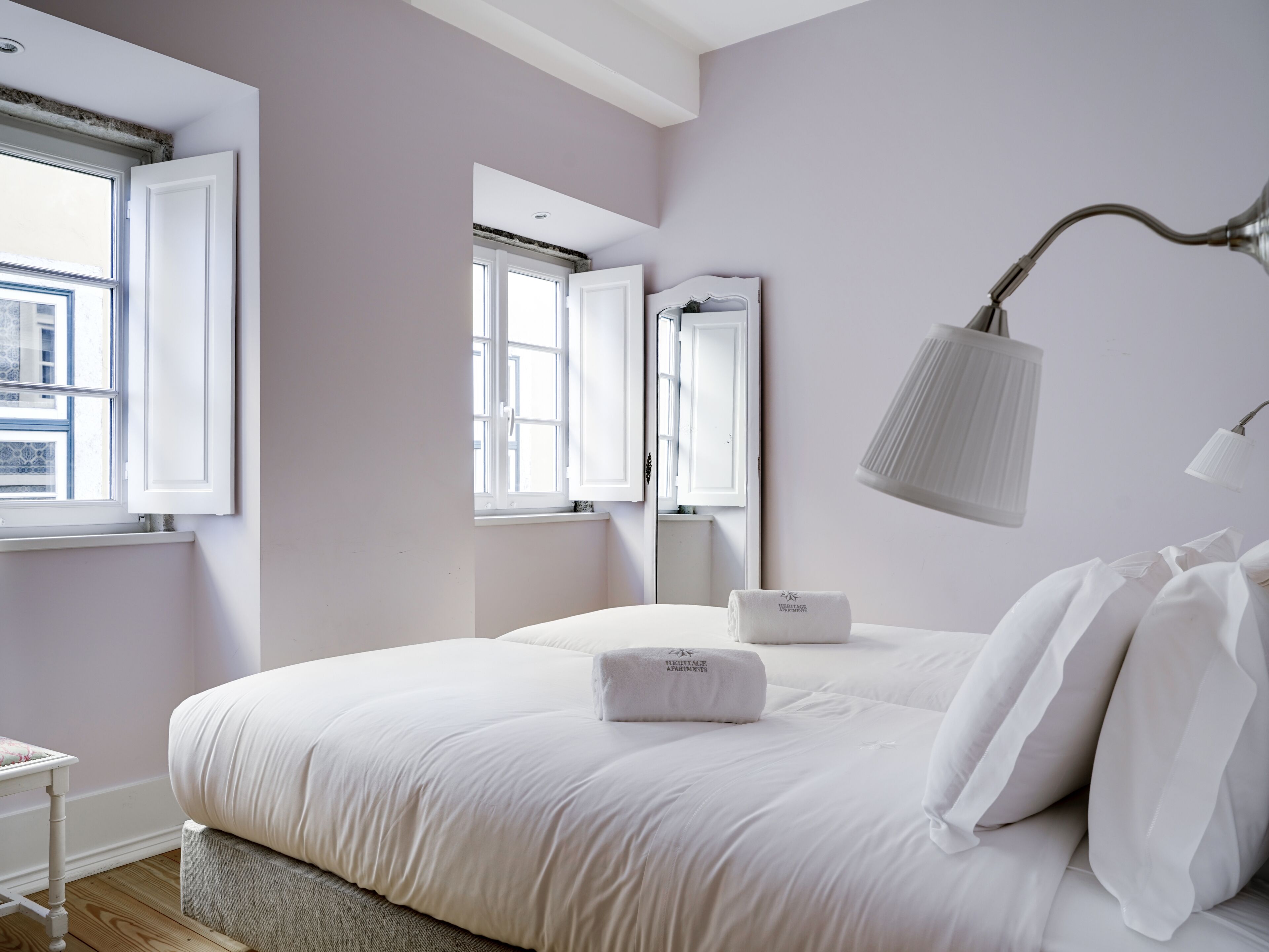 Een slaapkamer met een groot bed, nachtkastje, spiegel en raam.