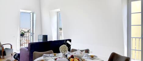A dining area with a round table set for four, surrounded by chairs.