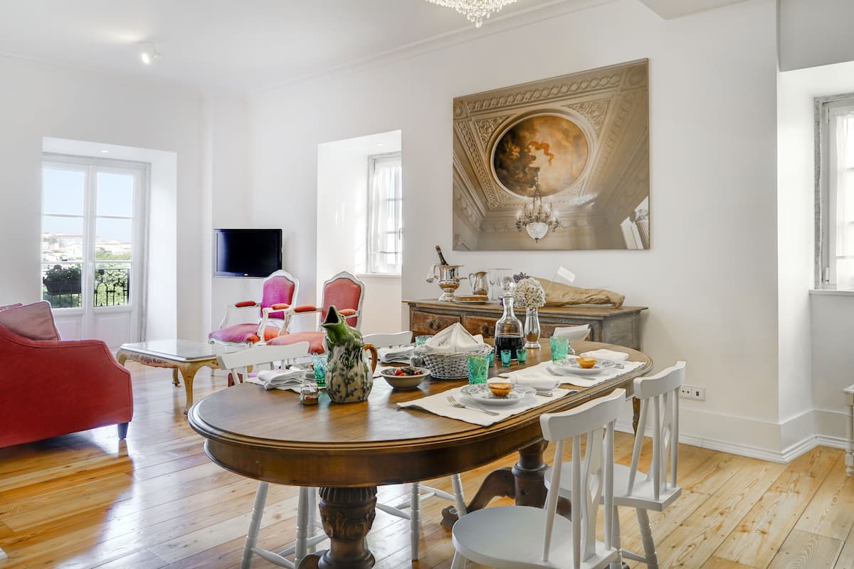 Un coin repas avec une table ronde, des chaises blanches et un lustre.