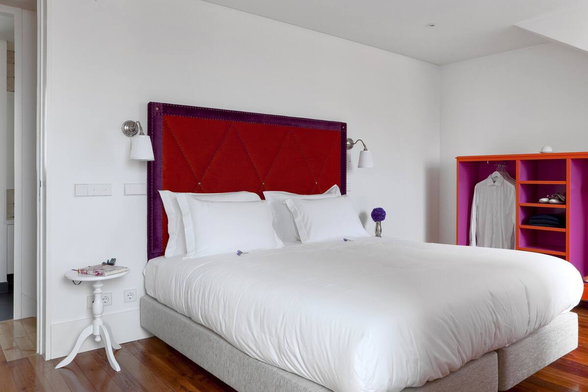 A neatly arranged bedroom with a large bed, a bedside table, a small table, and a wardrobe.