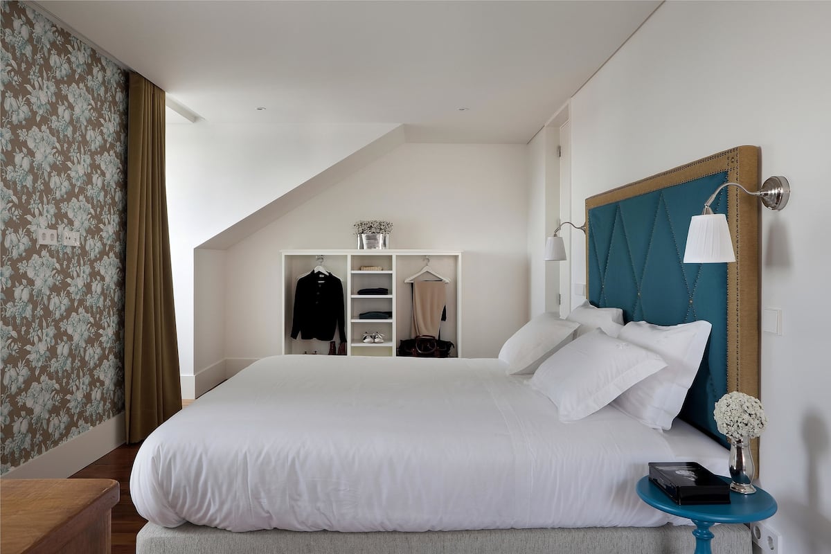 A bedroom with a large bed, a wardrobe, a bedside table, and a hanging light fixture.
