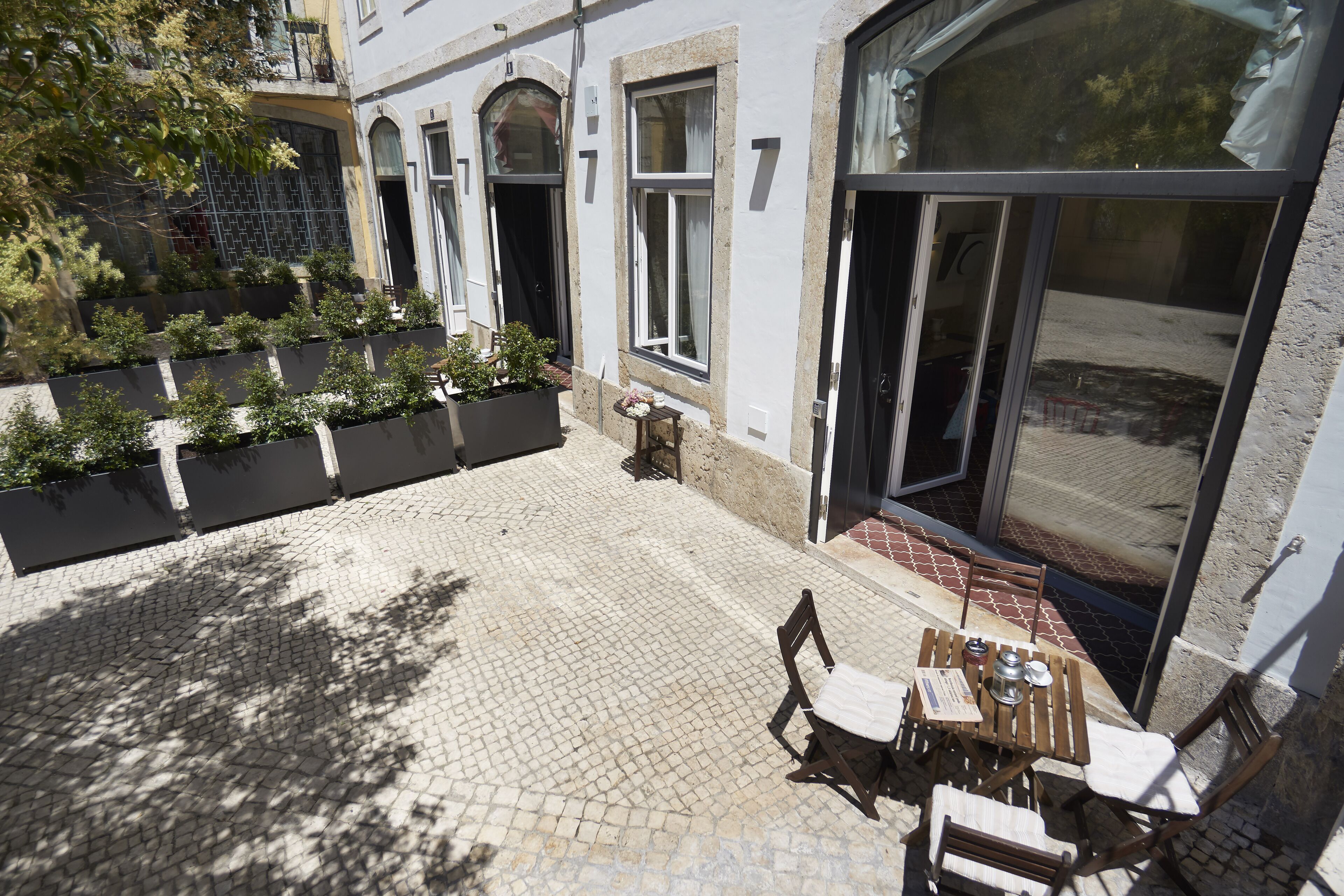 A courtyard with a tiled floor, a table with chairs, and a potted plant.