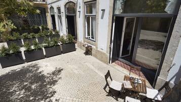 A courtyard with a tiled floor, a table with chairs, and a potted plant.