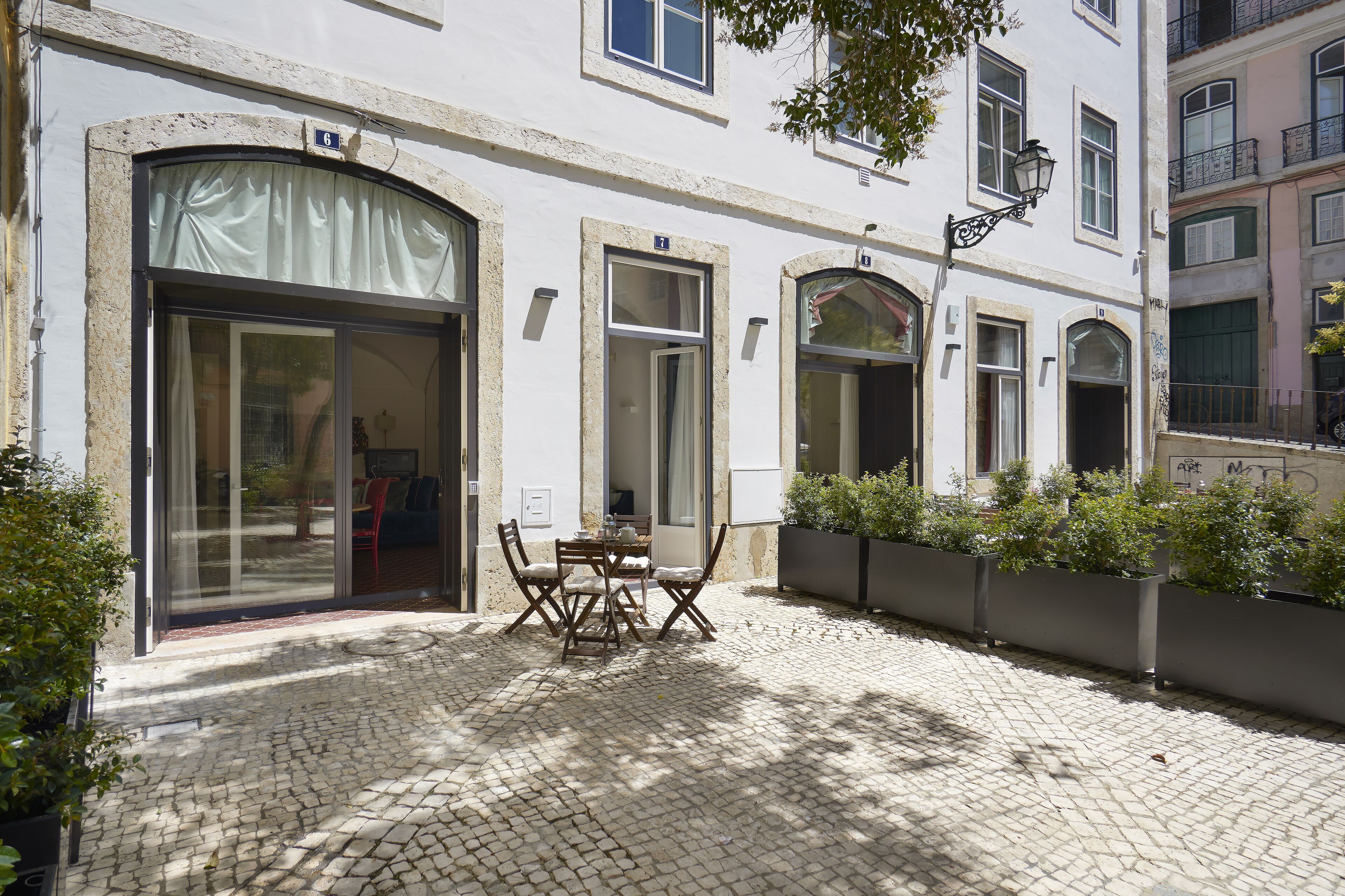 A courtyard with a table and chairs, a large window, and a door.