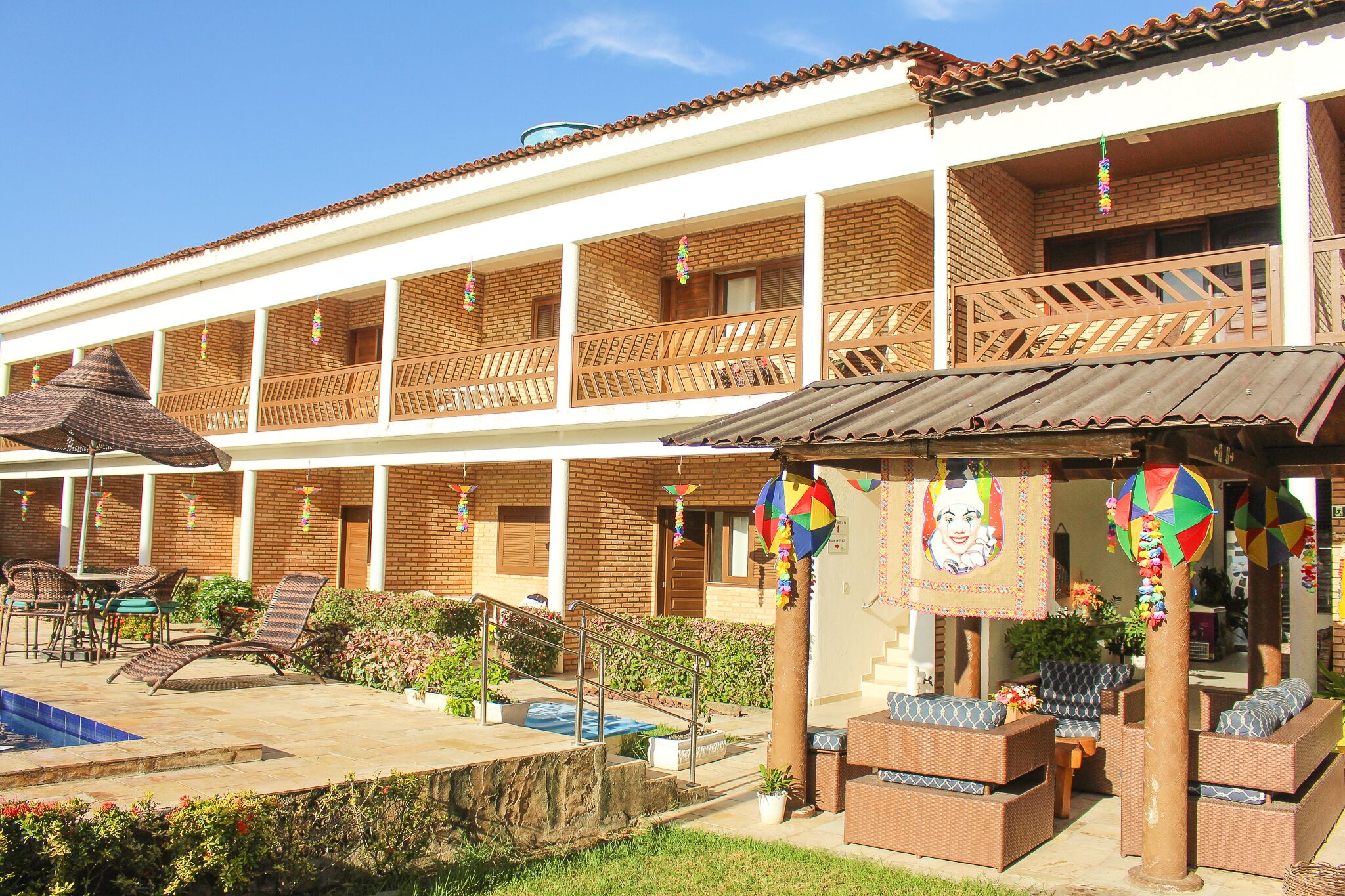 A two-story building with a swimming pool, outdoor seating, and a covered patio area.