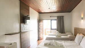 Une chambre d’hôtel avec deux lits, une télévision, un plafond en bois et une fenêtre avec des rideaux.